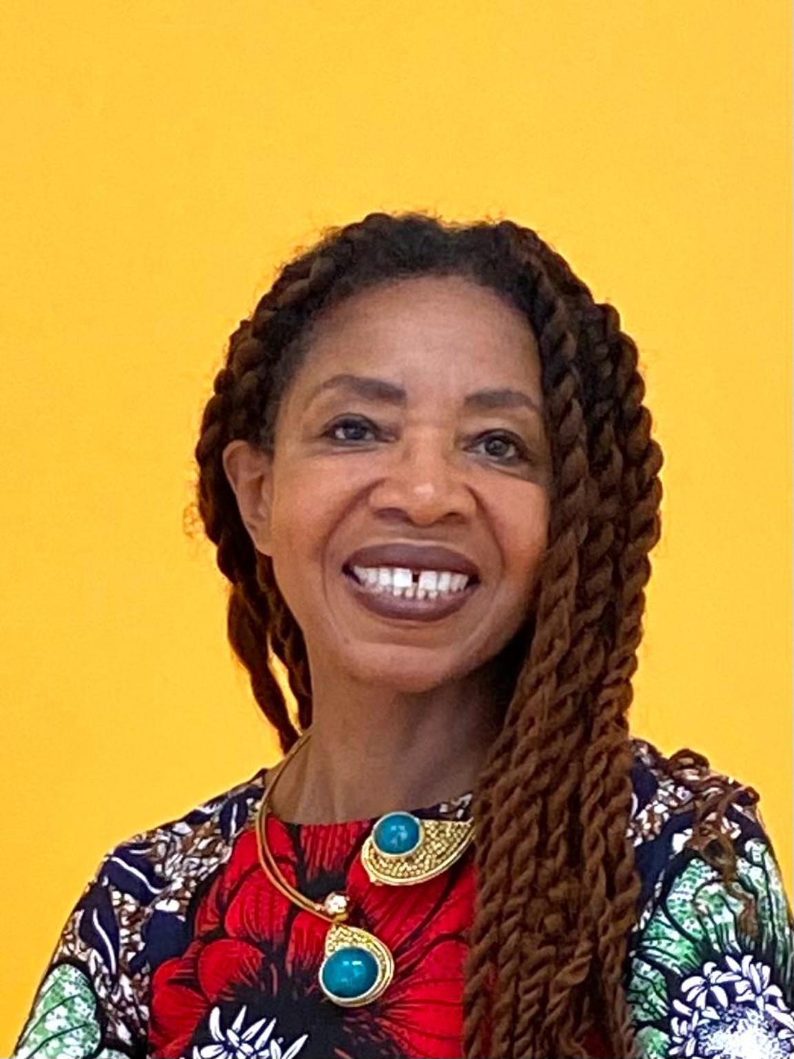 Shirley J. Thompson smiling in a vibrant portrait against a yellow background